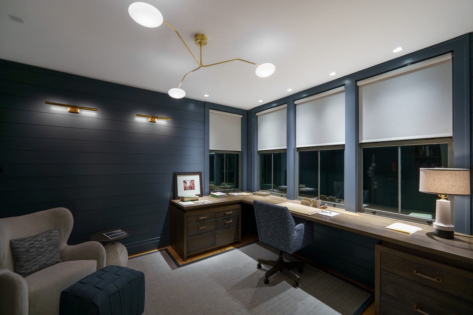 Home office with Lutron Palladiom roller shades half lowered and designer lighting